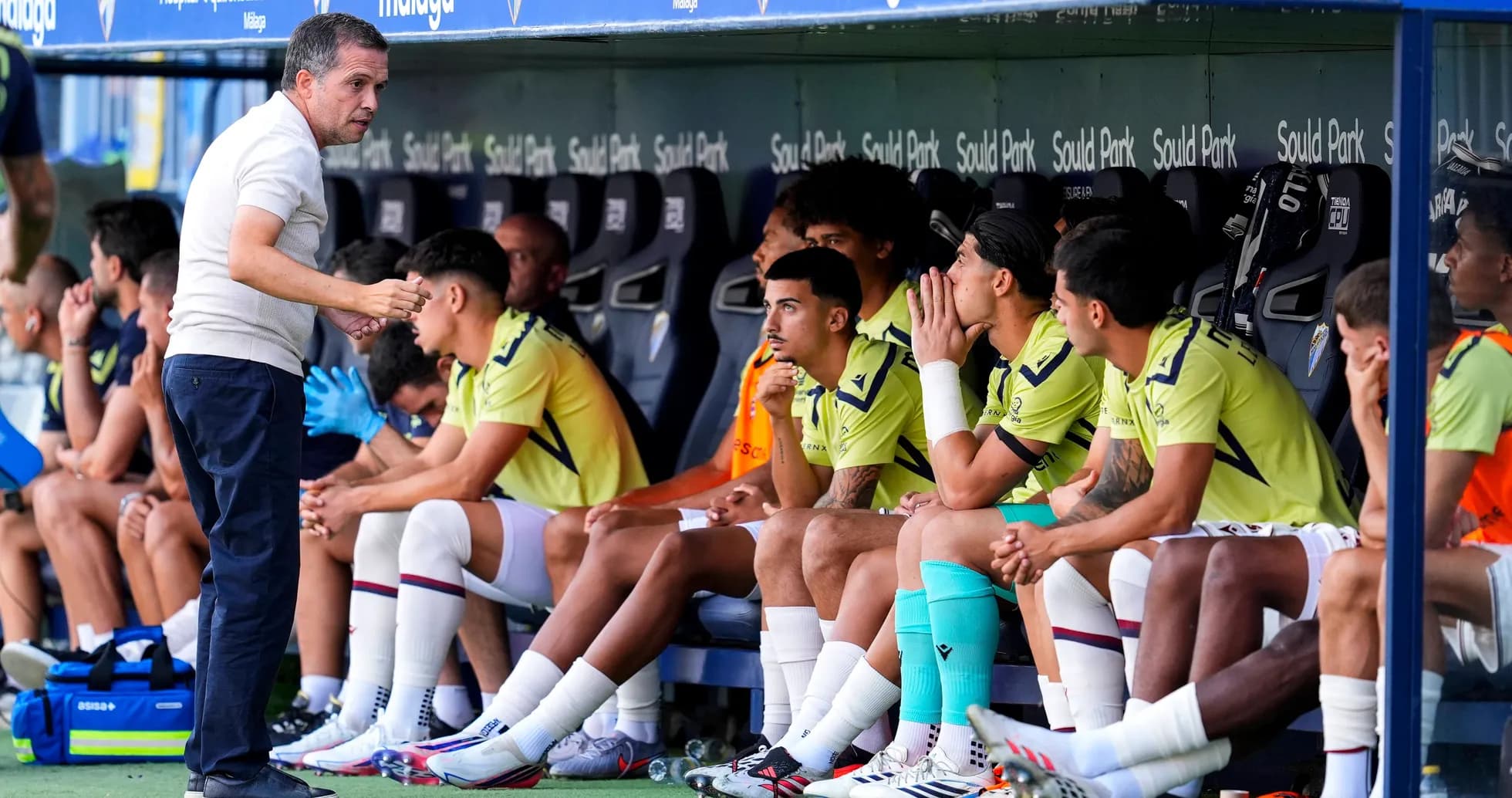 Entrenador dando instrucciones a jugadores en el banquillo