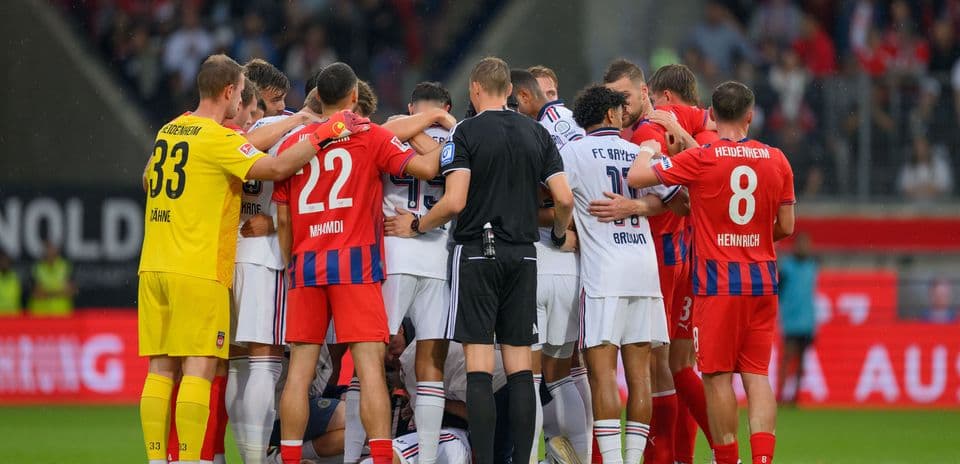 Jugadores de ambos equipos en un abrazo grupal
