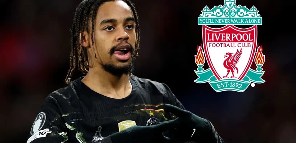 Jugador señalando el escudo de Liverpool en el campo