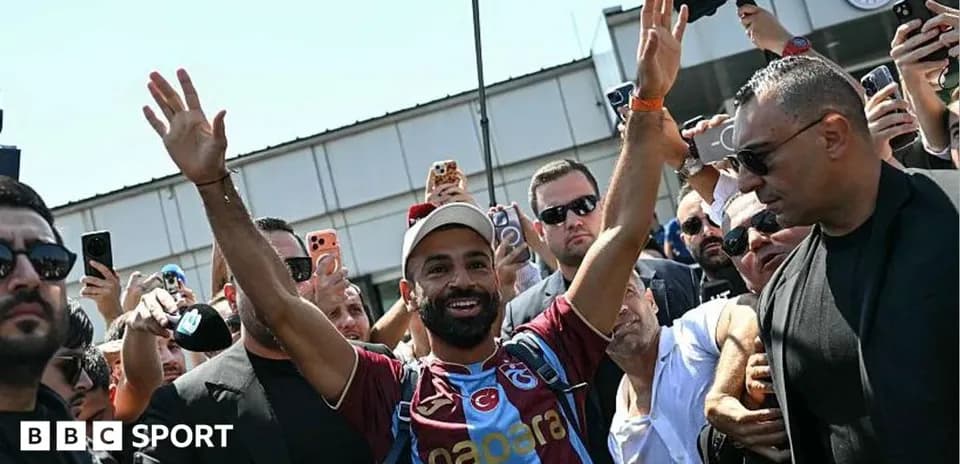 Jugador saludando a aficionados en el aeropuerto