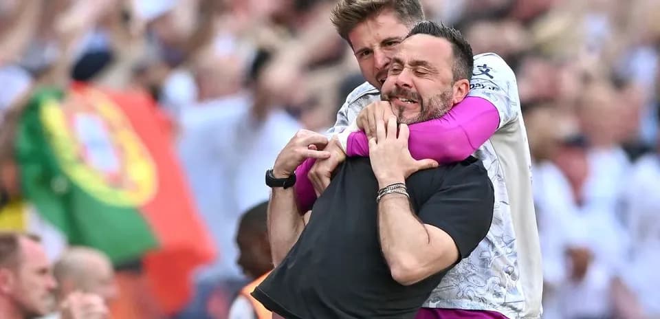 Dos entrenadores celebrando con un abrazo en el campo