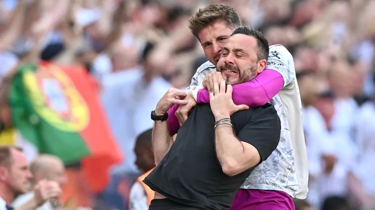 Dos entrenadores celebrando con un abrazo en el campo
