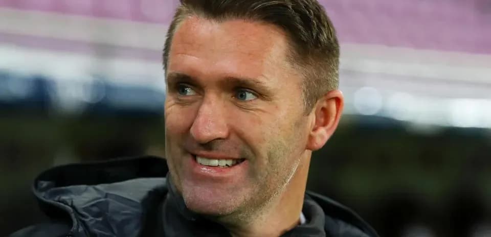 Entrenador sonriendo durante la previa del partido