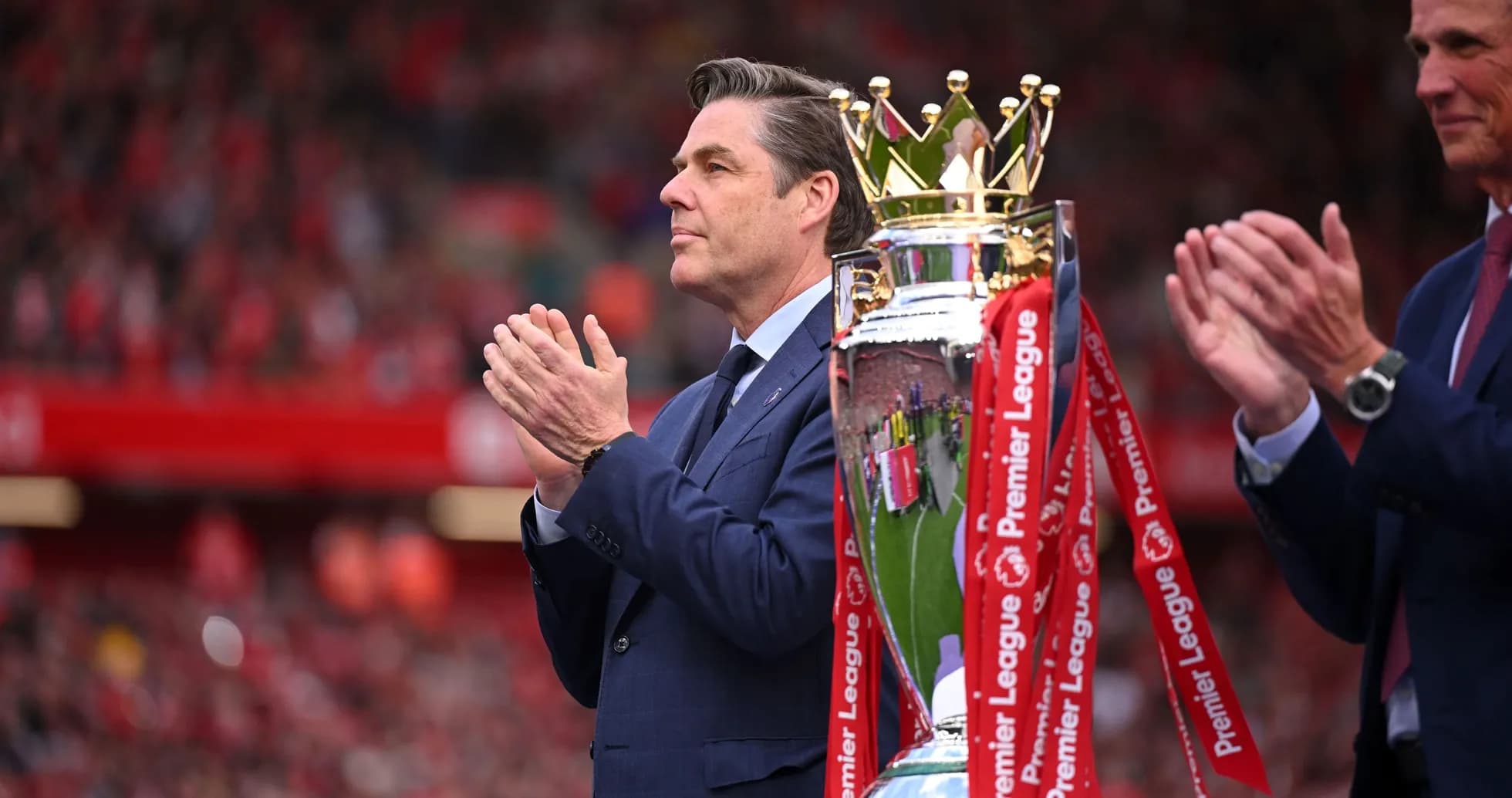 Hombre aplaudiendo junto al trofeo de Premier League