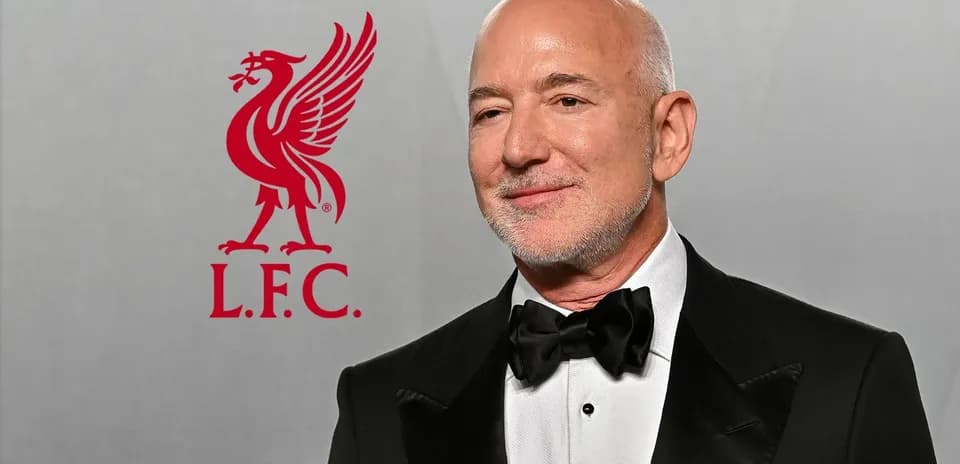 Hombre con traje negro posando junto al logo de Liverpool