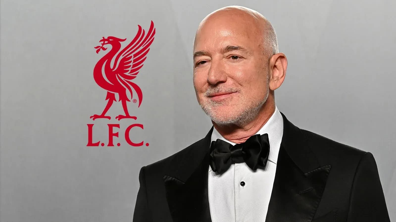 Hombre con traje negro posando junto al logo de Liverpool