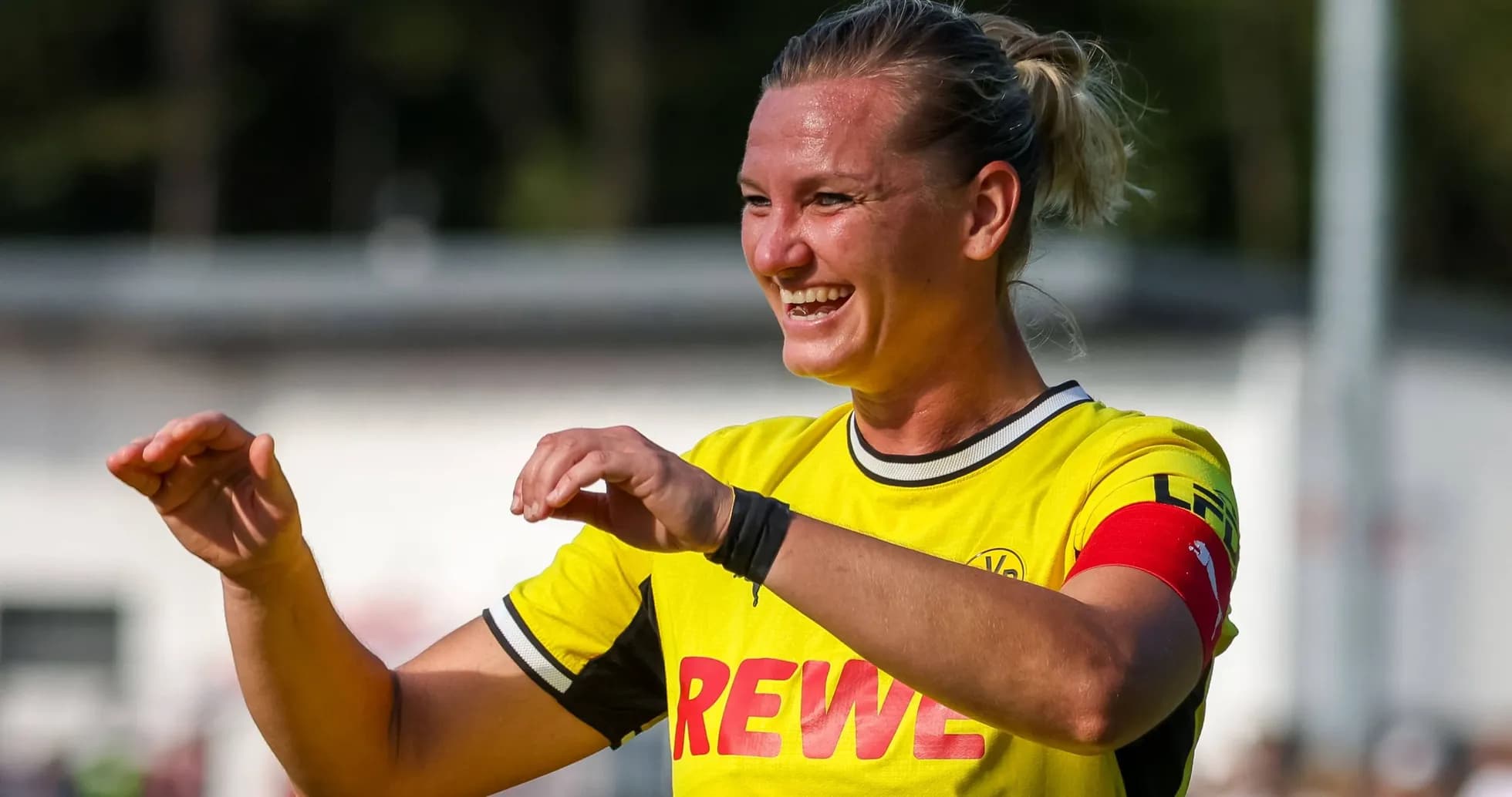 Jugadora sonriente con camiseta amarilla y brazalete