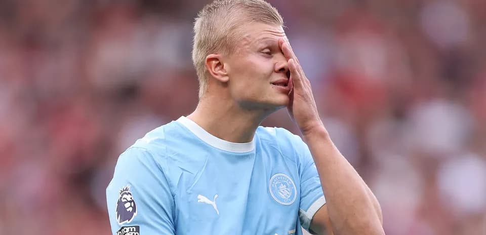 Jugador de Manchester City tocándose la cara en el campo