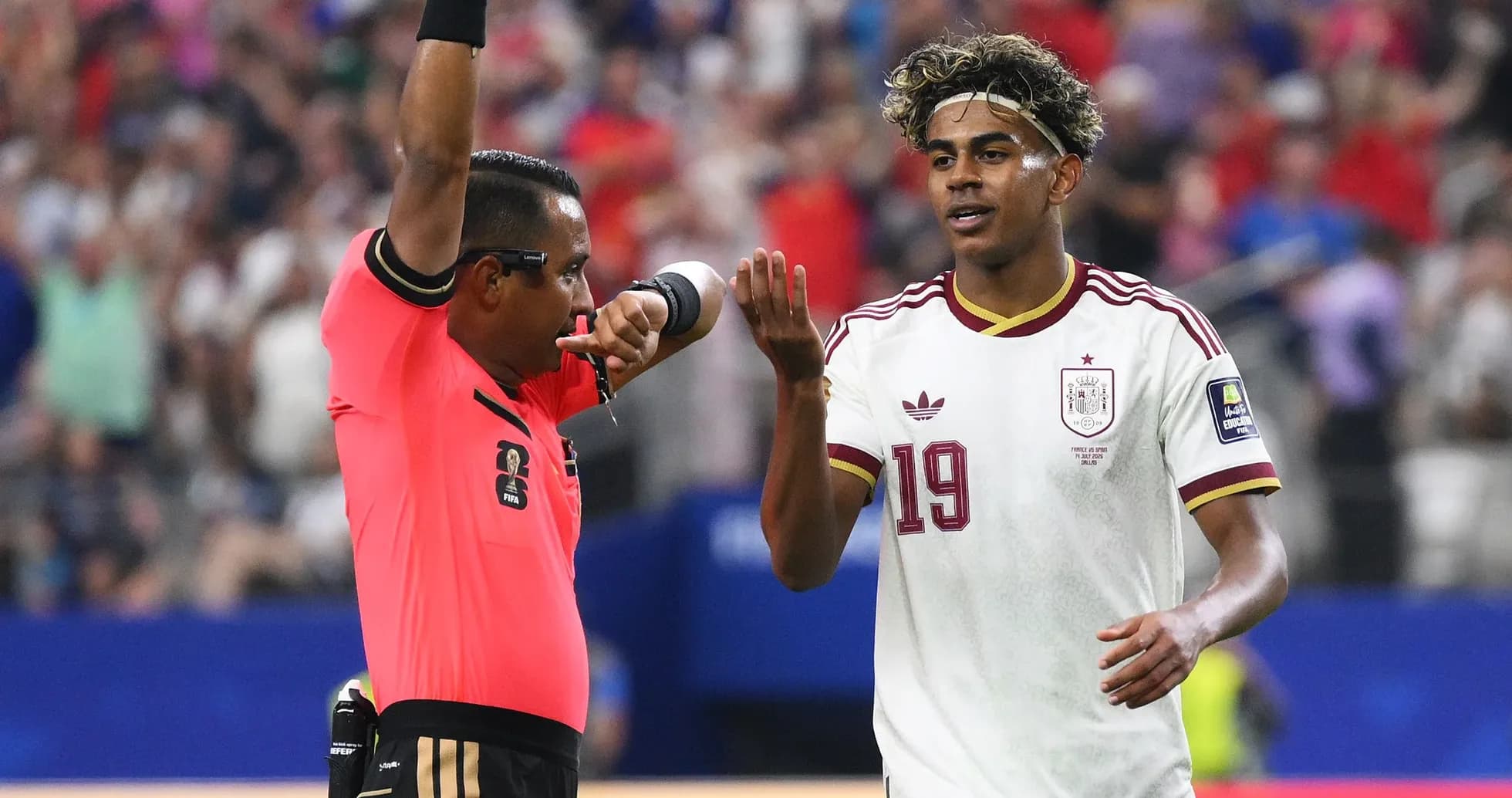 Árbitro mostrando tarjeta amarilla a jugador español