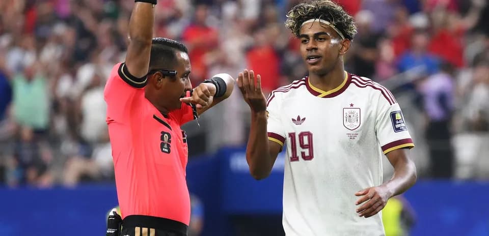 Árbitro mostrando tarjeta amarilla a jugador español