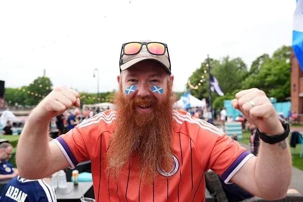 A fan celebrating with face paint and orange jersey
