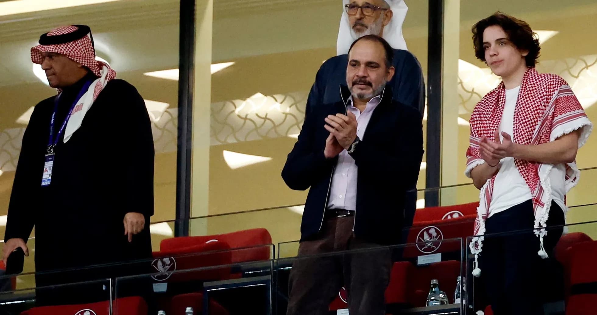 Cuatro personas aplaudiendo en el palco del estadio