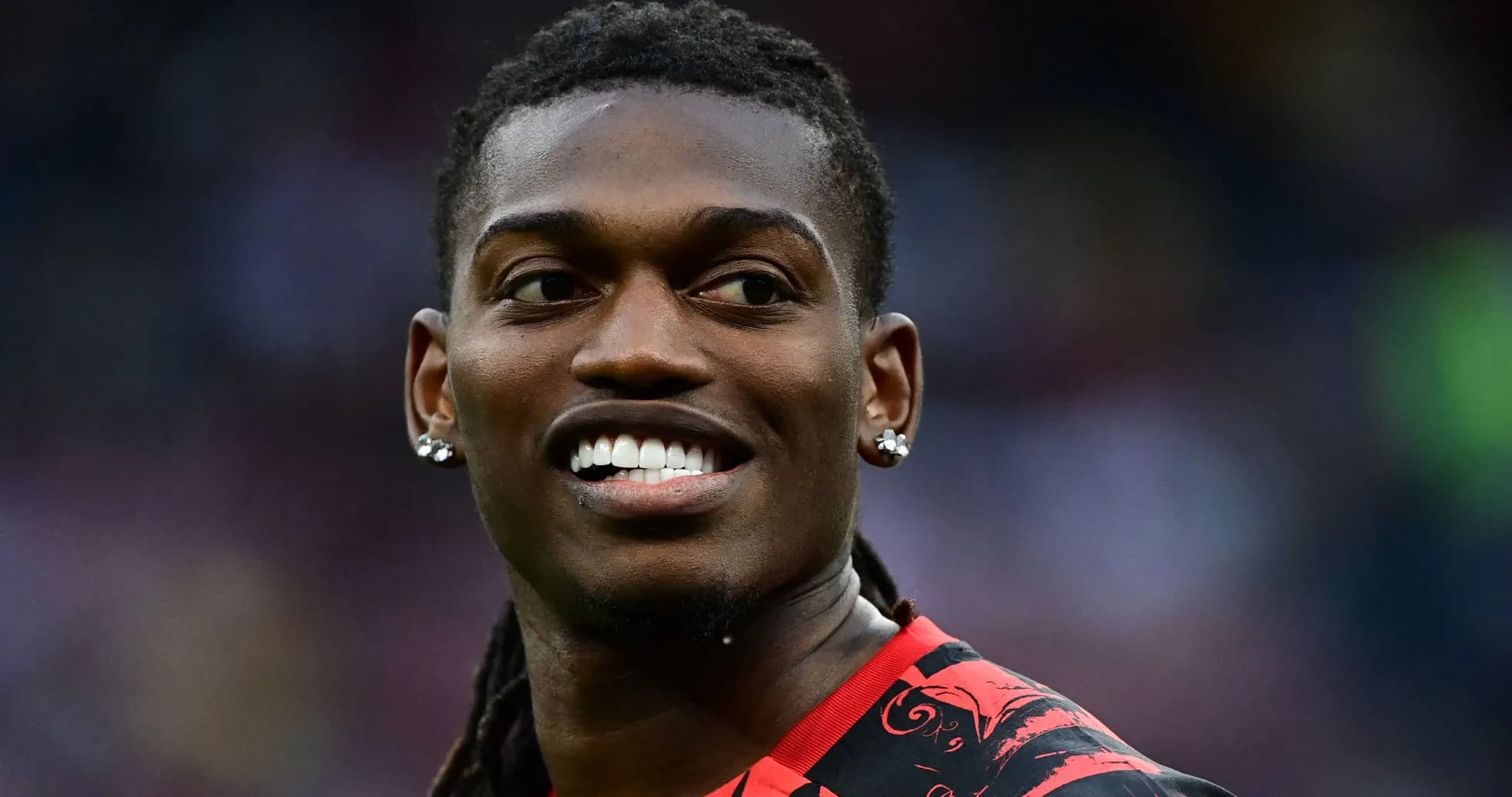 Jugador sonriendo con camiseta roja en el campo
