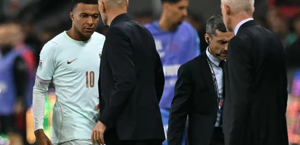 Kylian Mbappé conversando con entrenadores en el campo