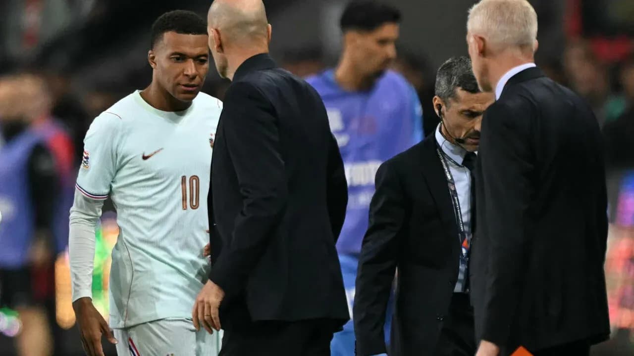 Kylian Mbappé conversando con entrenadores en el campo