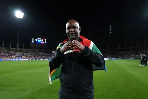 Entrenador sosteniendo bandera sudafricana en el campo