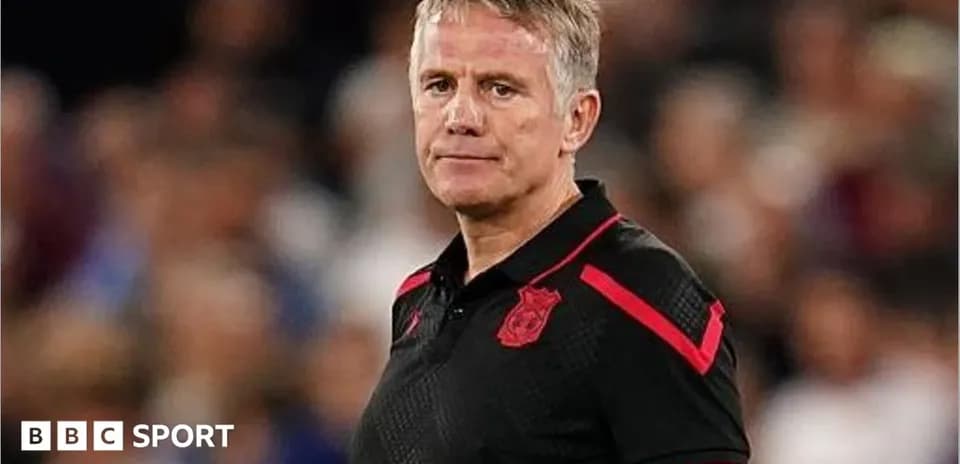 Entrenador de pie en el banquillo durante el partido