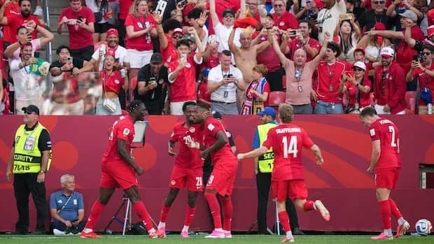 Jugadores celebrando un gol con aficionados de fondo
