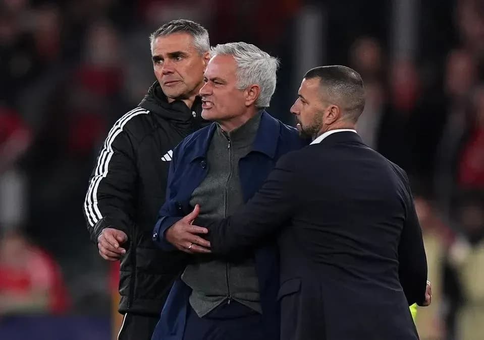 Entrenador siendo contenido por asistentes en el campo