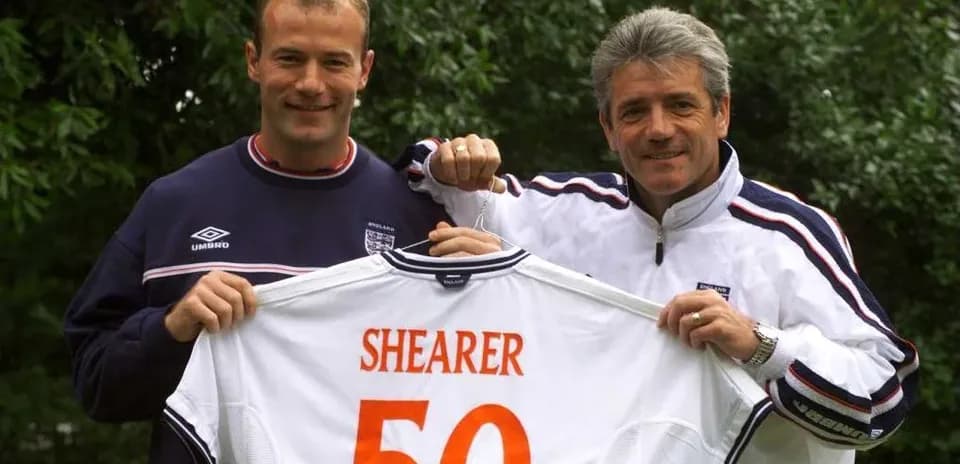 Alan Shearer y entrenador sosteniendo camiseta con número 50