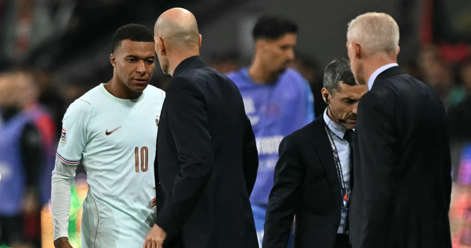 Kylian Mbappé conversing with coaches on the pitch