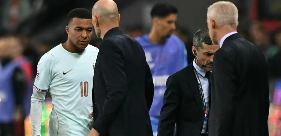 Kylian Mbappé conversing with coaches on the pitch