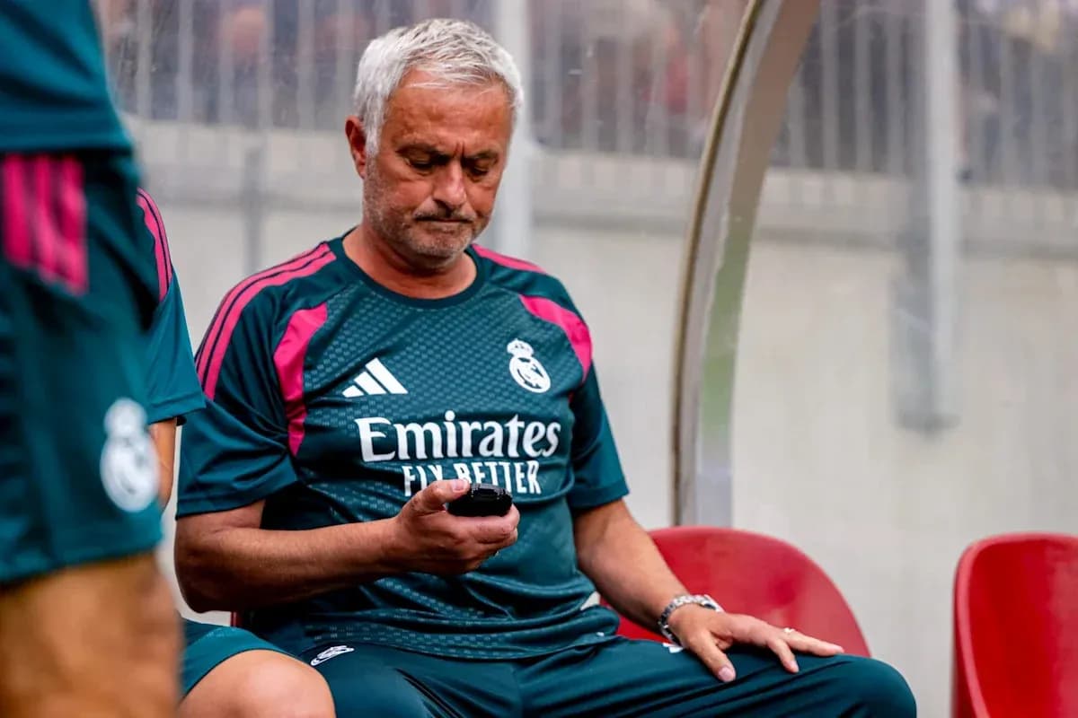 Entrenador sentado revisando su teléfono en el banquillo