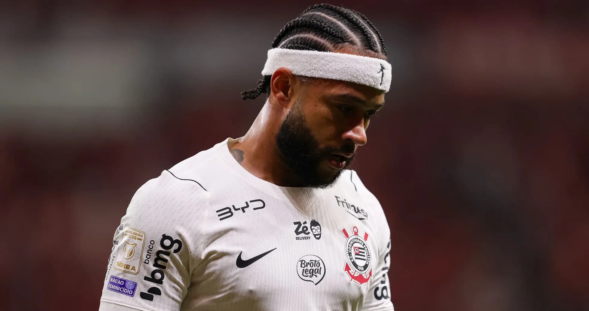 Jugador de fútbol con camiseta blanca mirando hacia abajo