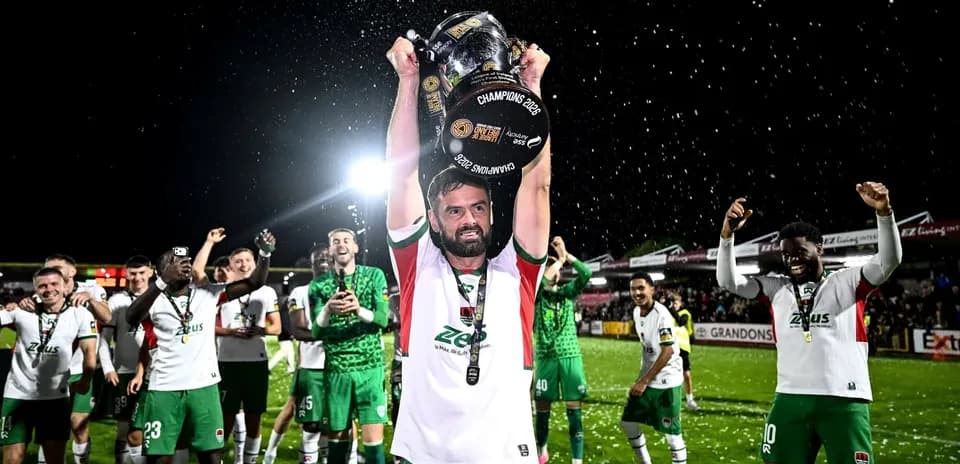 Jugador levantando trofeo con equipo celebrando detrás