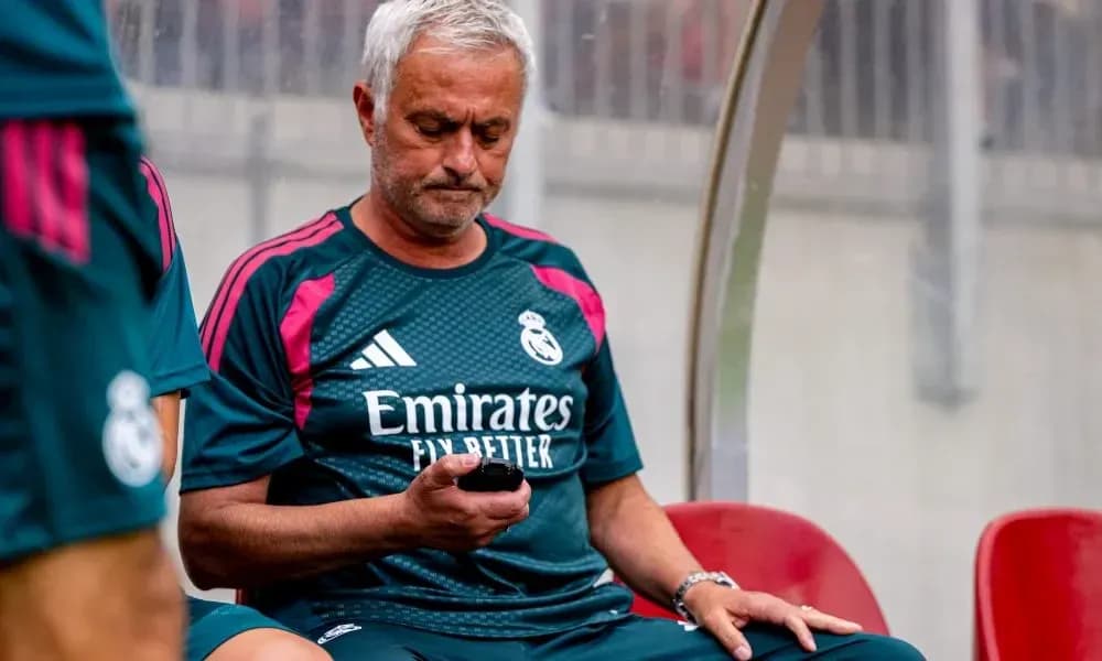 Entrenador de Real Madrid revisando su teléfono en banquillo