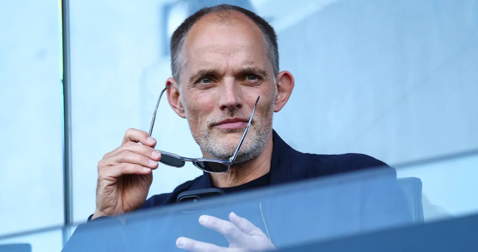 Hombre sosteniendo gafas en un palco de estadio