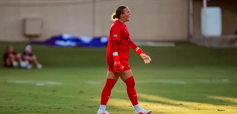 Portera con uniforme rojo caminando en el campo