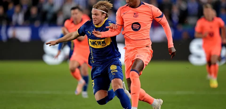 Jugador de Alavés siendo tackleado por jugador de Barcelona