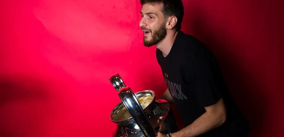 Jugador sosteniendo un trofeo frente a fondo rosa