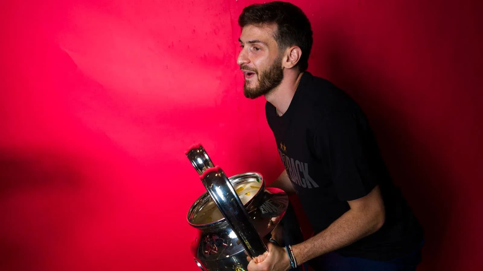 Jugador sosteniendo un trofeo frente a fondo rosa