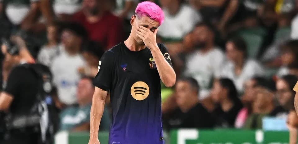 Jugador con cabello rosa cubriéndose la cara en el campo