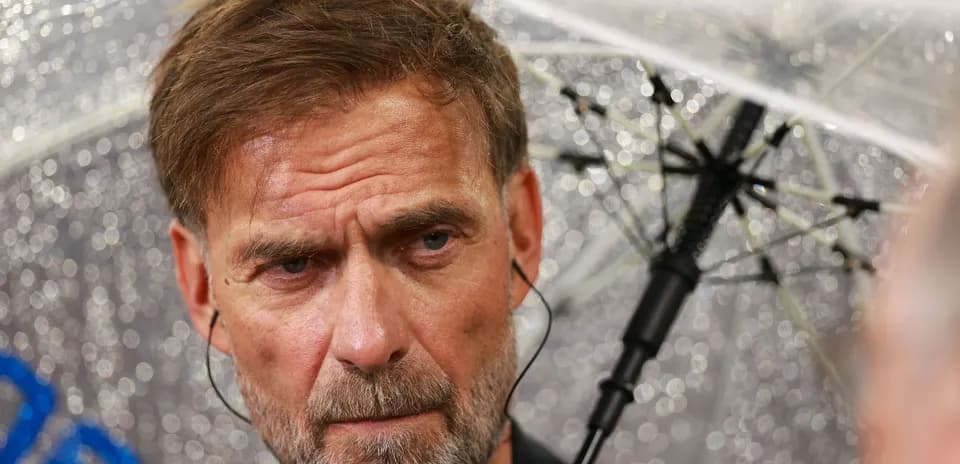 Entrenador hablando bajo un paraguas en la lluvia