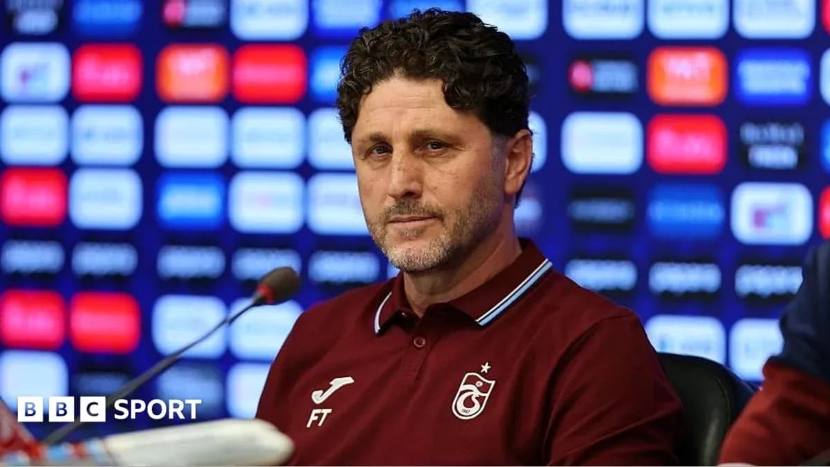 Entrenador en conferencia de prensa con fondo gráfico