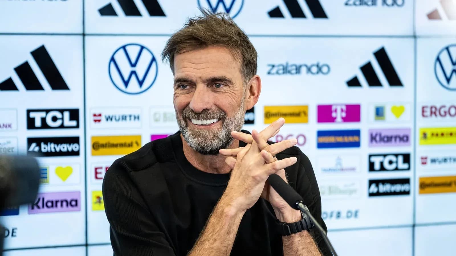 Entrenador en conferencia de prensa sonriendo