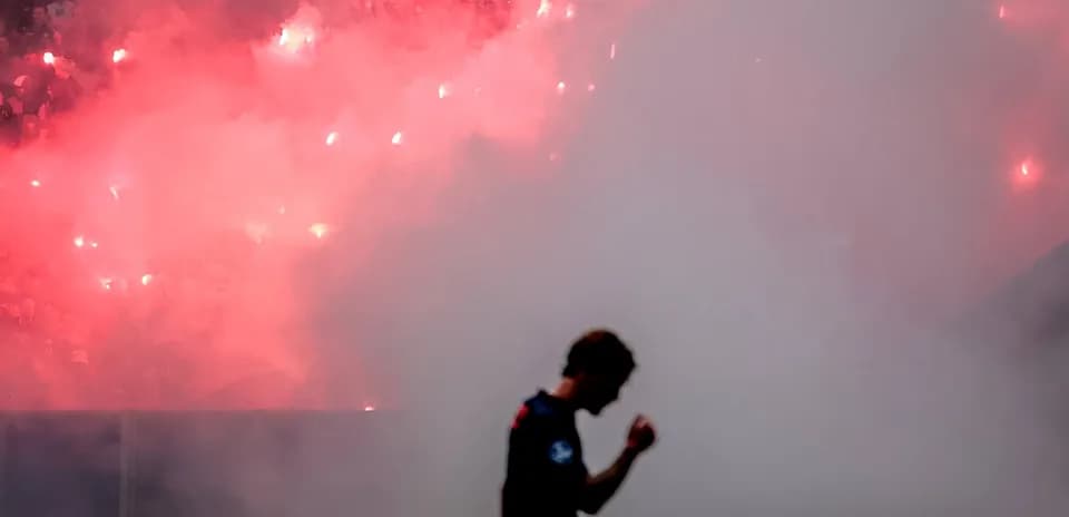 Jugador celebrando con humo y bengalas en fondo