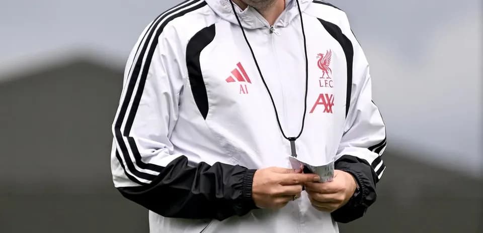 Entrenador de Liverpool sonriendo en el campo de entrenamiento