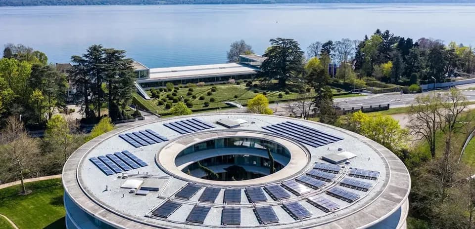 Vista aérea de edificio con paneles solares y lago