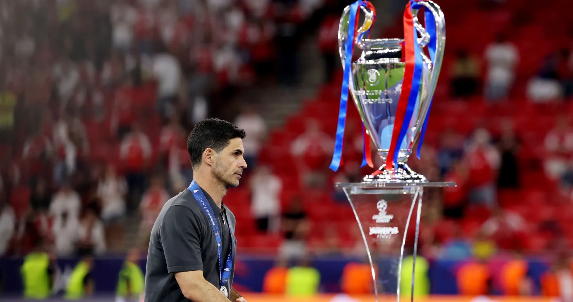 Entrenador caminando junto al trofeo de la Champions