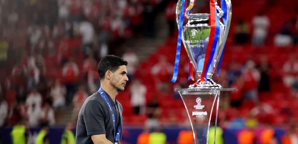 Entrenador caminando junto al trofeo de la Champions