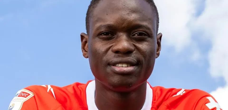 Jugador sonriendo con camiseta roja frente a cielo