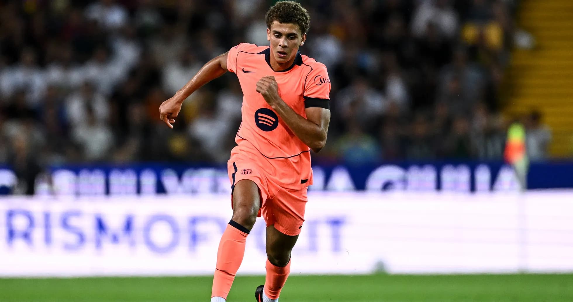 Jugador corriendo con uniforme naranja en el campo