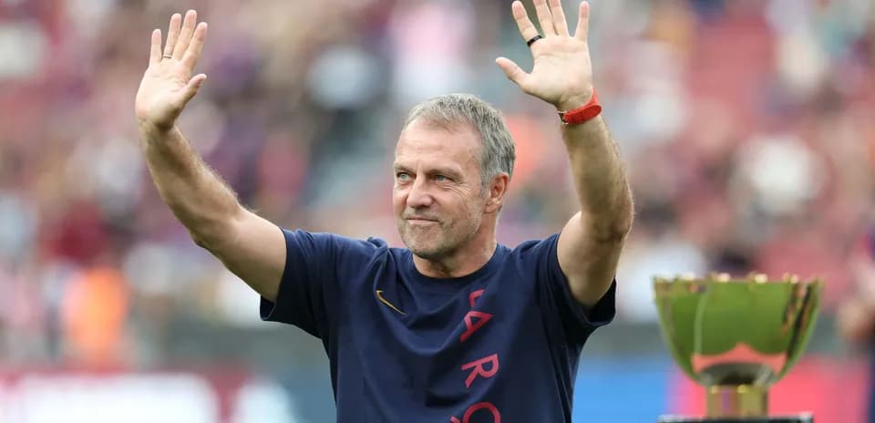Entrenador saludando junto a un trofeo en el campo