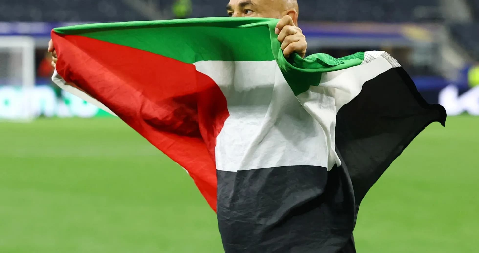 Persona sosteniendo una bandera palestina en el campo