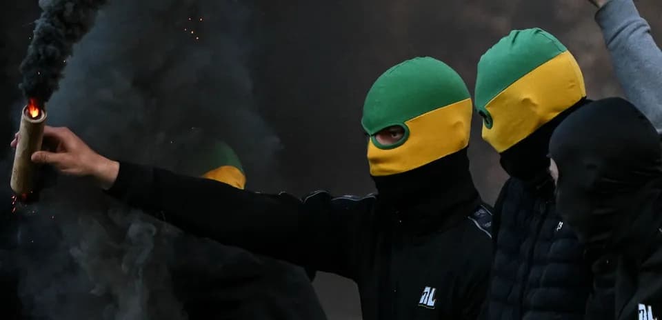 Grupo de personas con máscaras y bengalas encendidas