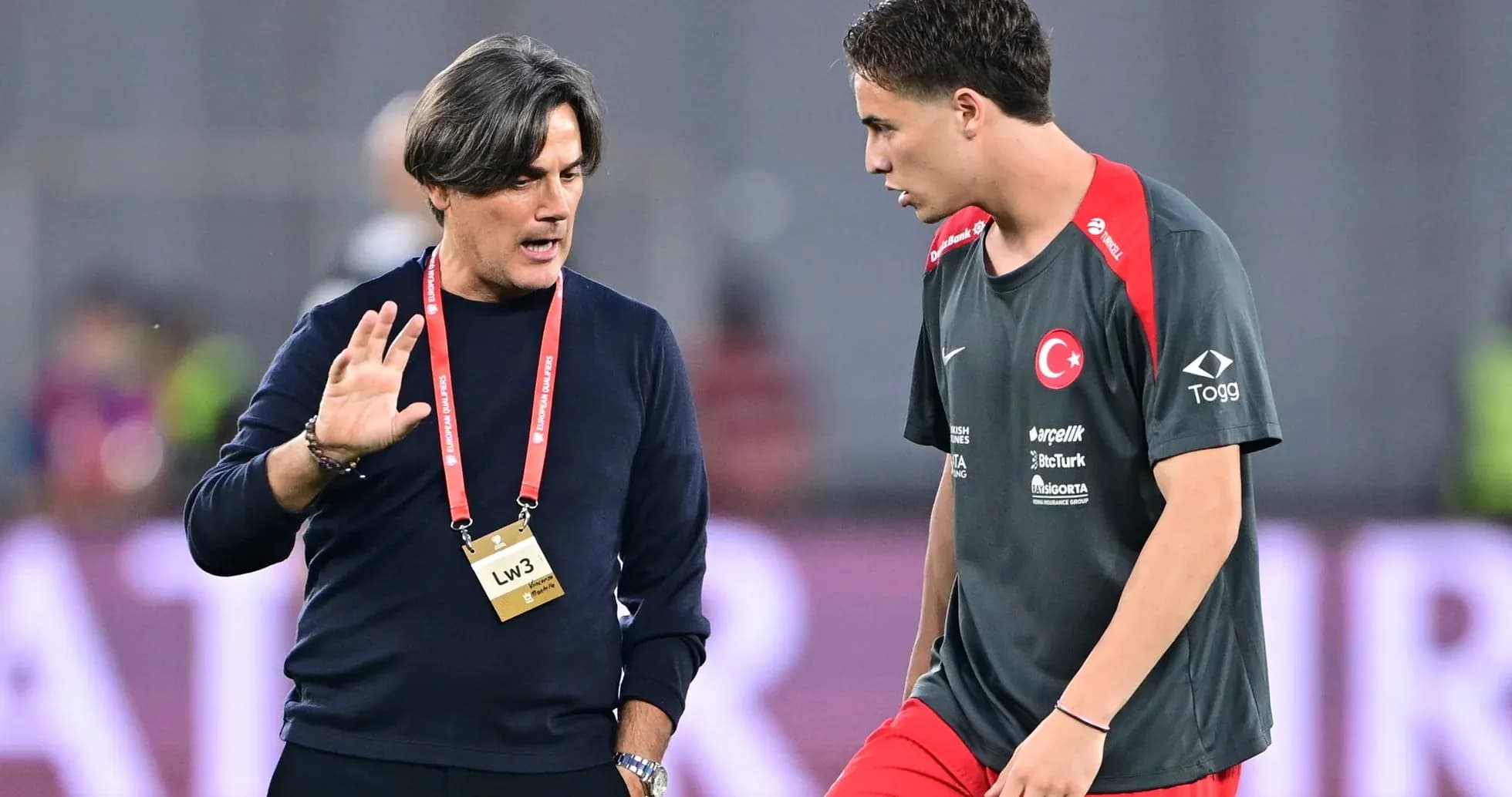 Entrenador hablando con jugador en campo de entrenamiento